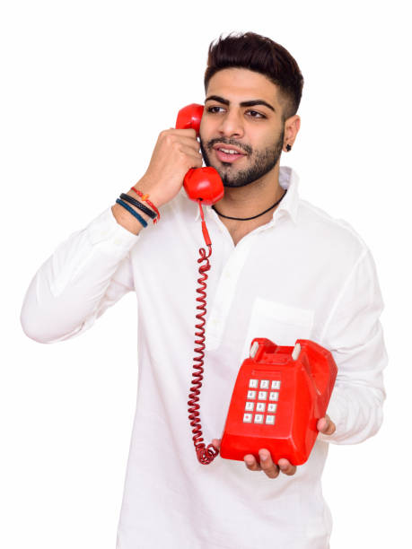 istock Young happy Indian man smiling while thinking and talking on old telephone 668526630
