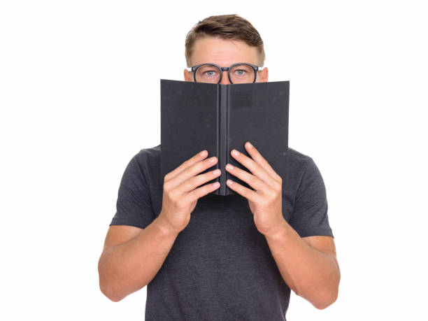 istock Young handsome nerd man wearing eyeglasses while covering face with book 668530532