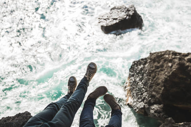 istock Hipsters legs in sneakers on a sea cliff 668533770