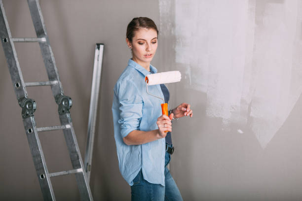 istock beautiful young woman looking at wall and holding roller 668533830