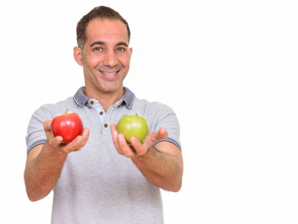 istock Mature happy Persian man smiling while giving red apple and green apple 668541362