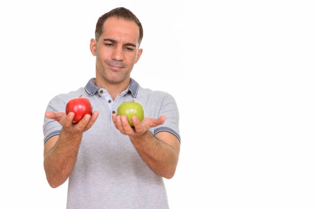 istock Mature handsome Persian man choosing between red apple and green apple 668541380