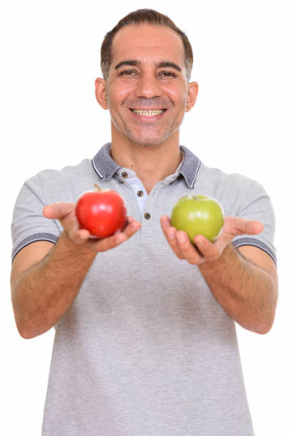 istock Mature happy Persian man smiling while holding red apple and green apple 668541382