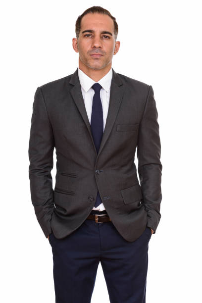 istock Mature handsome Persian businessman standing with hands in pockets 668544700