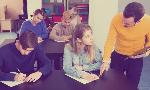 istock Male teacher clearing up complicated issue to pupil during exam in class 668550124