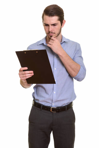 istock Young handsome Caucasian businessman standing and reading on clipboard while thinking 668550854