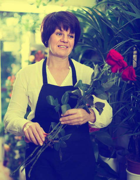 istock Adult shop assistant displaying bright red roses 668554204