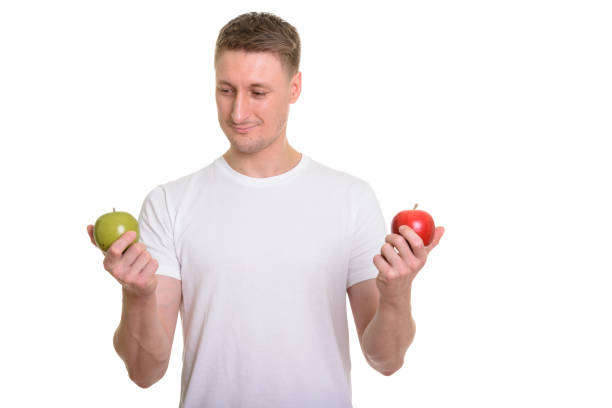 istock Handsome man looking at green apple while holding red apple ready for gym 668557866