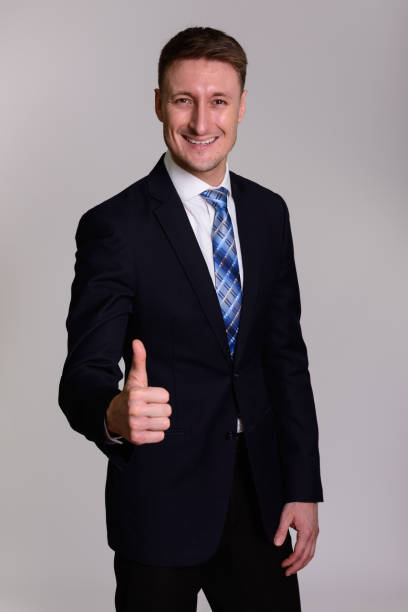 istock Happy handsome businessman smiling while giving thumb up against gray background 668560976