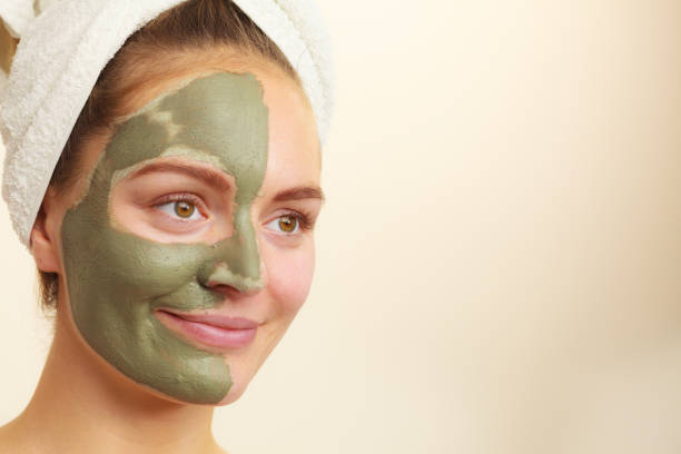 istock Woman face with green clay mud mask 668561578