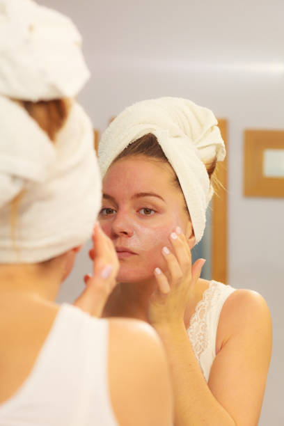 istock Woman applying mask cream on face in bathroom 668568904