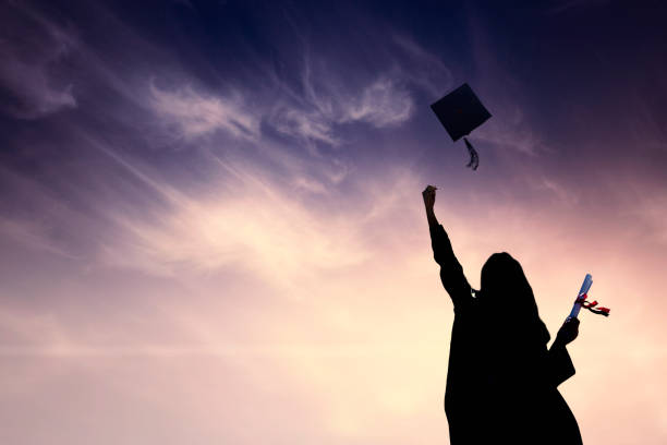 istock Graduate students tossing up hats over blue sky 668569264