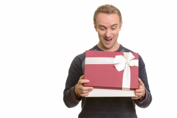 istock Happy handsome man smiling while opening gift box and looking surprised 668571992