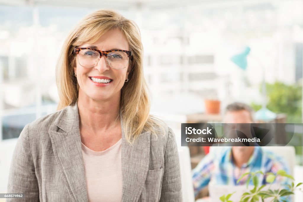 Lässige Geschäftsfrau vor ihrer Kollegin lächelnd - Lizenzfrei Frauen Stock-Foto