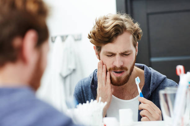 Sensitive teeth Man with sensitive teeth touching his cheek toothache stock pictures, royalty-free photos & images