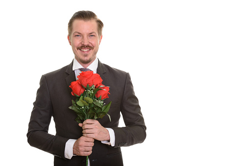 Young happy businessman holding red roses with both hands ready for Valentine's day horizontal shot