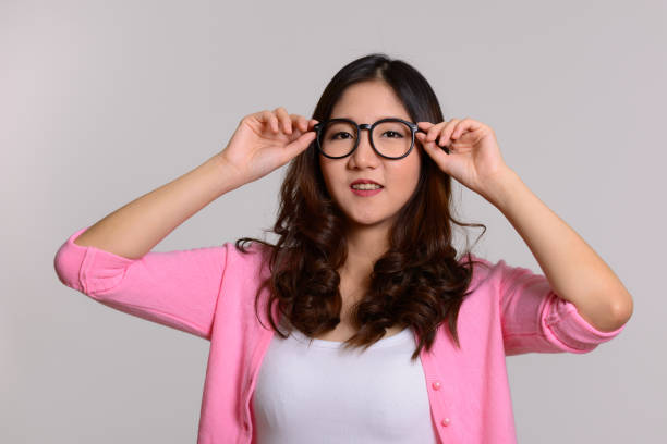 istock Young happy Asian woman smiling while holding eyeglasses 668581698