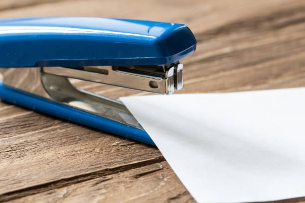 istock blue stepler and paper sheet on wooden background 668581728