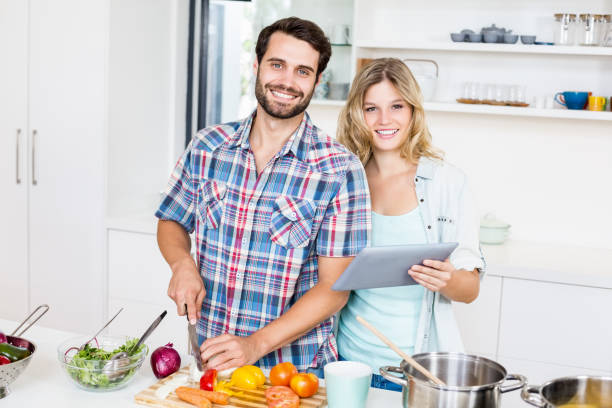 istock Young couple chopping vegetable and holding digital tablet 668581966