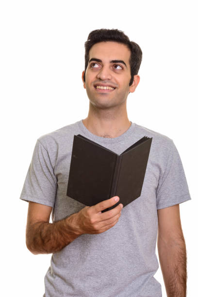istock Young happy Persian man smiling and holding book while thinking 668582390