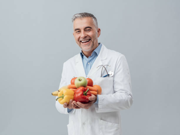 Smiling nutritionist holding fresh vegetables and fruit Smiling nutritionist holding fresh vegetables and fruit: healthcare and healthy vegetarian diet concept nutritionist stock pictures, royalty-free photos & images