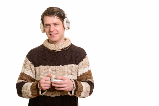 Happy handsome man smiling while wearing winter earmuffs and holding coffee cup horizontal shot