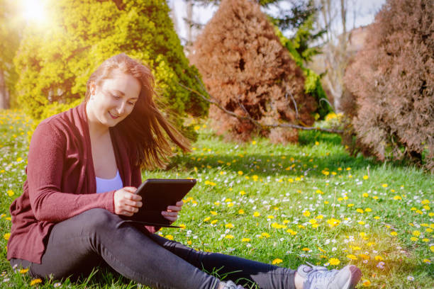 istock Beautiful young woman using digital tablet outdoors 668589134