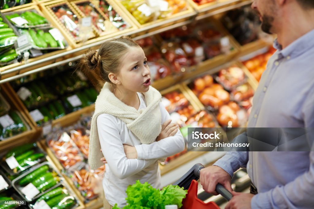 Grumpy girl Little daughter asking her father for something in supermarket Child Stock Photo