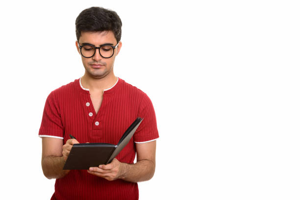 istock Young handsome Persian man writing on diary while wearing eyeglasses 668596212