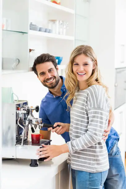 Portrait of young couple preparing coffee from coffeemaker at home