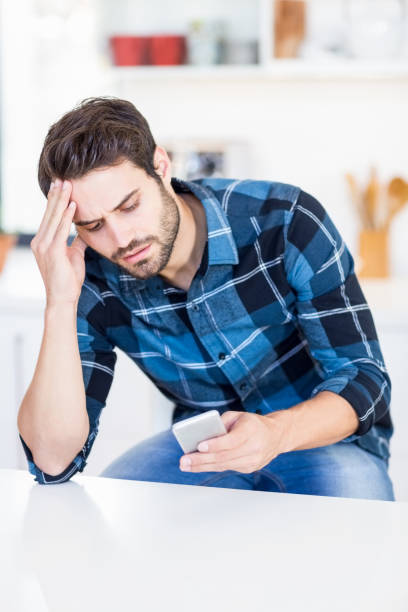 istock Worried man text messaging on mobile phone 668596404