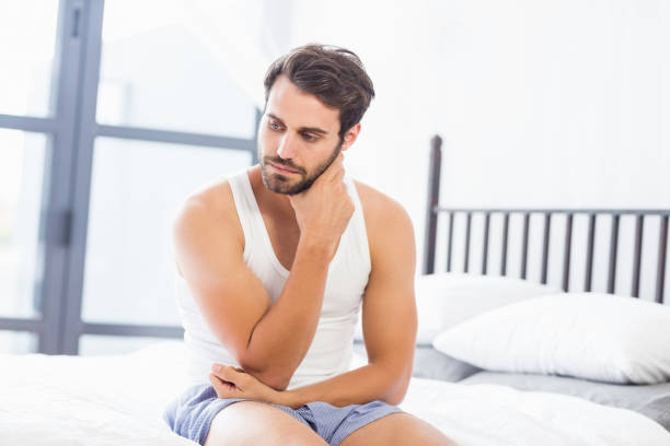 istock Tensed young man sitting on bed 668596948