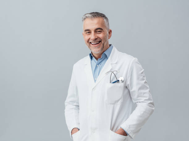 Cheerful doctor posing Cheerful mature doctor posing and smiling at camera, healthcare and medicine laboratory coat stock pictures, royalty-free photos & images