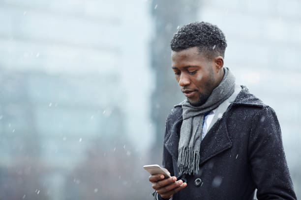 istock Handsome African Man with Smartphone in Snow 668600078