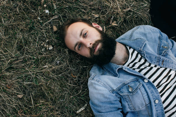istock bearded man lying on the grass in the park 668602620