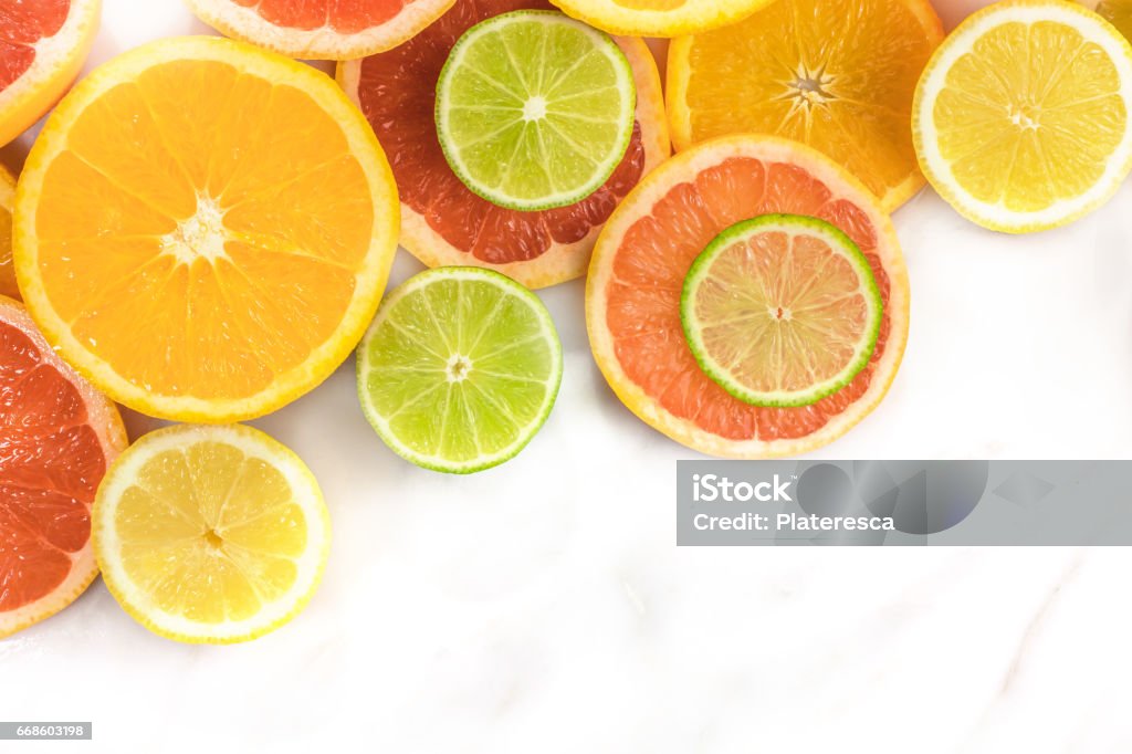 Grapefruit, lime, lemon, and orange slices with copyspace Vibrant juicy citrus fruits on a white marble texture with copy space. Grapefruit, lime, lemon, and orange slices Citrus Fruit Stock Photo