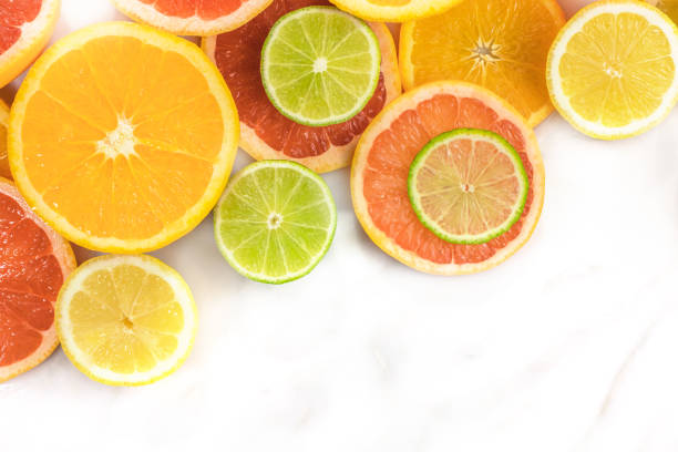 Grapefruit, lime, lemon, and orange slices with copyspace Vibrant juicy citrus fruits on a white marble texture with copy space. Grapefruit, lime, lemon, and orange slices citrus fruit stock pictures, royalty-free photos & images