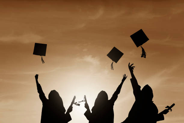istock Graduate students tossing up hats over sky 668607170