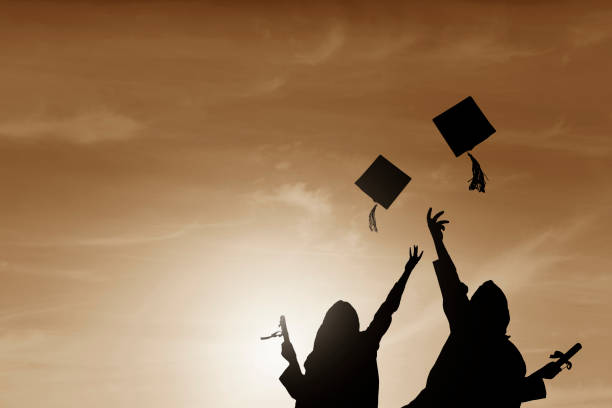 istock Graduate students tossing up hats over sky 668607174