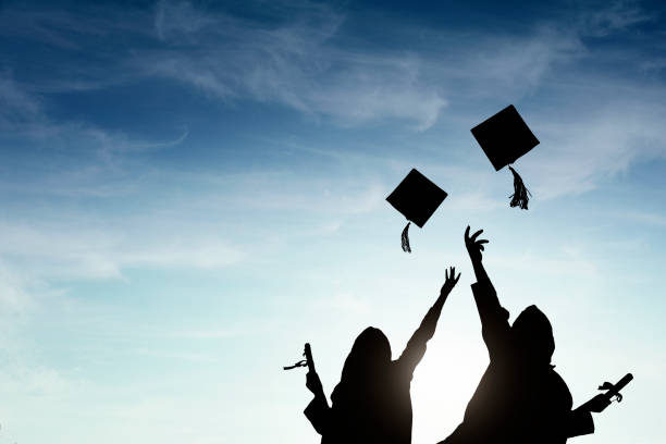 istock Graduate students tossing up hats over sky 668607178