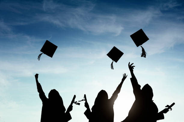 istock Graduate students tossing up hats over sky 668607184