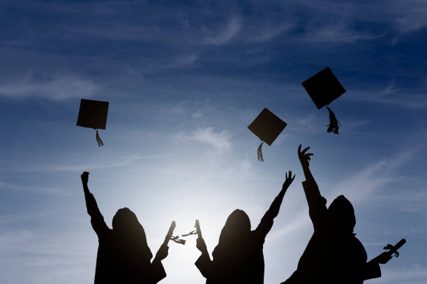 istock Graduate students tossing up hats over sky 668607188