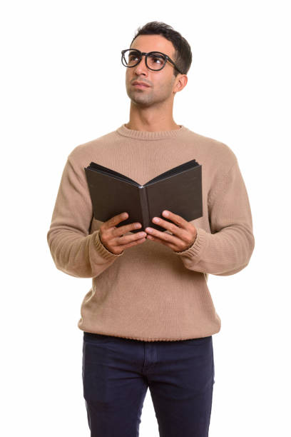 istock Young handsome Persian man standing while holding book and thinking 668609594