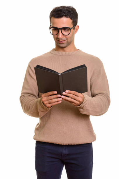 istock Young happy Persian man standing while reading book and wearing eyeglasses 668609598