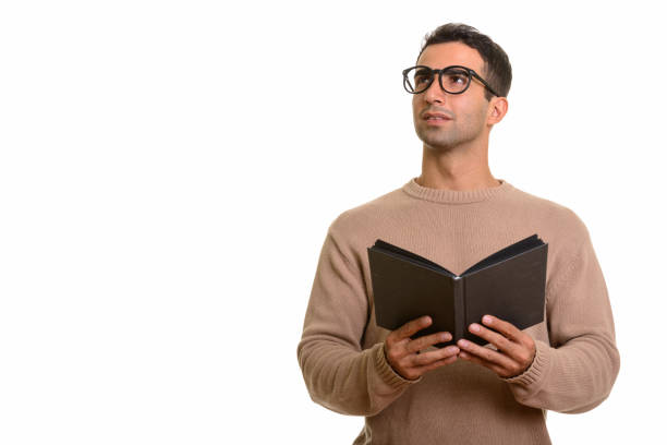 istock Young happy Persian man smiling while holding book and thinking 668609628