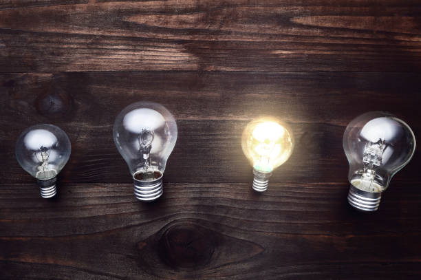 istock 4 light bulbs on a wooden background, one light is on, concept ideas, eurika 668612910