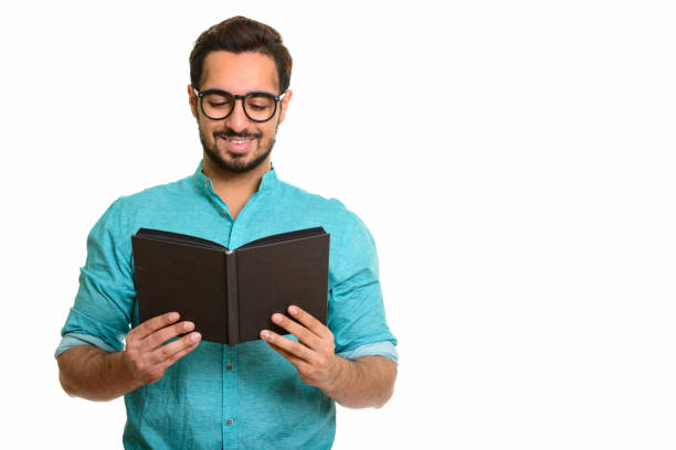 istock Young happy Indian man smiling while reading book with eyeglasses 668616568