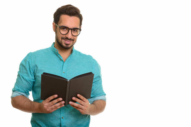istock Young happy Indian man smiling while holding book and wearing eyeglasses 668616596
