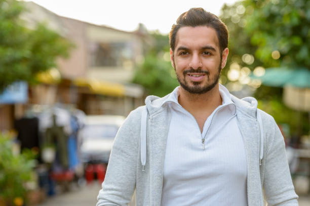 istock Young happy Indian man smiling while thinking outdoors 668617732