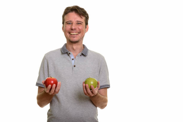 istock Happy handsome man smiling while holding red and green apple 668624022